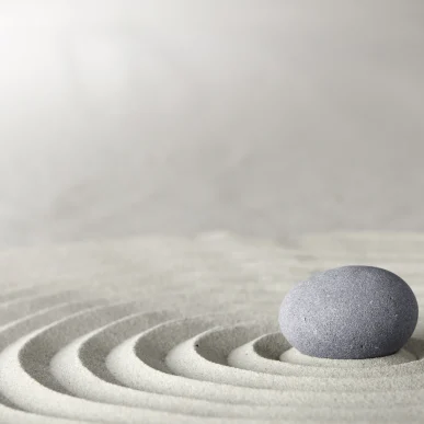stone sitting in center of patterned sand